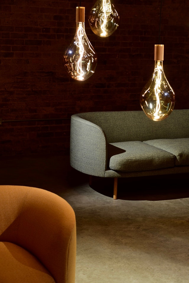 modern bir aydınlatma ile gri ve turuncu koltuklu salon dekorasyonu